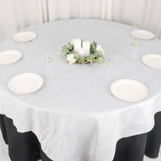 Elegant round table setup with white tablecloth, candles, and decorative plates.