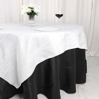 Elegant white and black tablecloth draped over a dining table with wine glass.