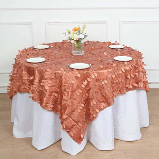 Round table with peach leaf-patterned tablecloth and floral centerpiece.