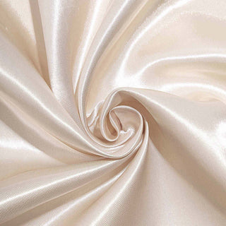 Silky beige fabric in a swirling pattern, showcasing smooth texture and sheen.