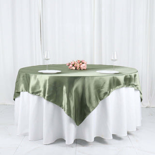 Elegant round table with olive green satin tablecloth and floral centerpiece.