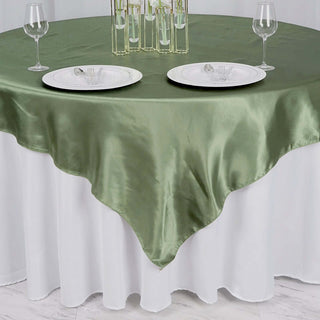Green satin tablecloth draped over a white table with plates and glasses.