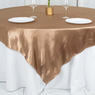 Brown satin tablecloth draped over a round table with plates and glasses.