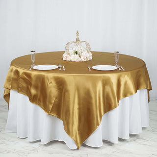 Elegant gold satin tablecloth draped over a round table with decor.