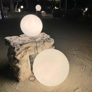 Outdoor round LED lights on a stone pedestal at night.