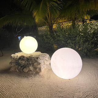 Two glowing orbs on a stone pedestal in a tropical outdoor setting.