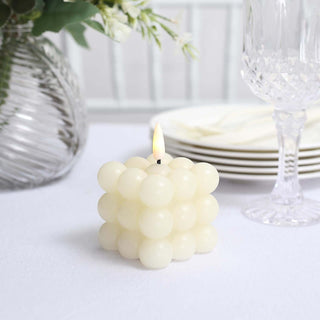 White bubble candle with a small flame on a table setting.