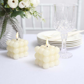 White bubble candles on a table with floral decor and glassware.