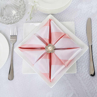 Elegant pink and white napkin folded on a plate with a decorative brooch.
