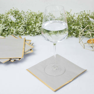 Elegant glass of water on a gold-edged napkin with floral backdrop.