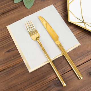 Gold cutlery set with fork and knife on a decorative napkin.