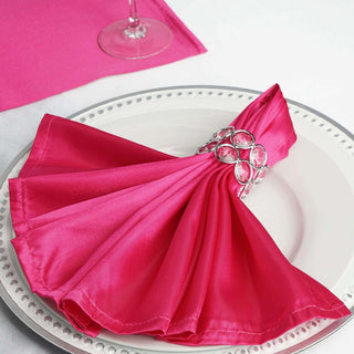 Pink satin napkin with decorative ring on a white plate.