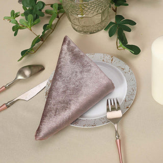 Elegant taupe napkin on a decorative plate with cutlery and greenery.