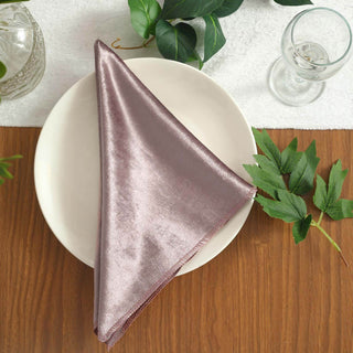 Elegant mauve satin napkin on a plate surrounded by greenery.