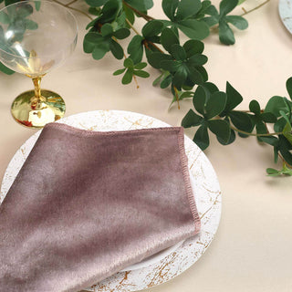 Elegant pink napkin on a decorative plate with greenery and a glass.