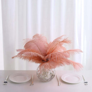 Pink feather arrangement in a clear vase on a dining table.