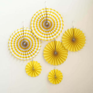 Yellow paper fan decorations in various sizes hanging on a wall.