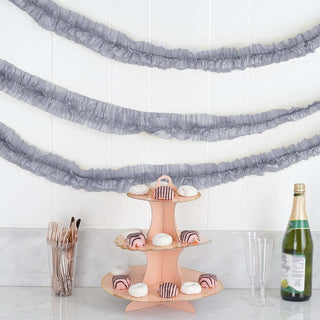 Three-tier pink cake stand with pastries, champagne bottle, and utensils.