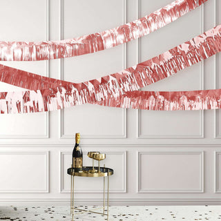 Rose gold party decorations with champagne and glasses on a stylish table.
