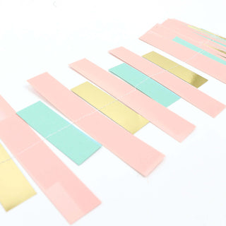 Colorful paper strips in pink, green, and gold arranged in a row.