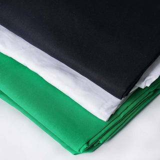 Stacked fabric rolls in black, white, and green on a neutral background.