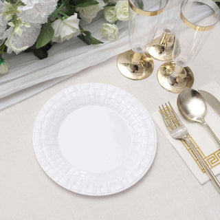 White decorative plate on a dining table with elegant glassware and cutlery.
