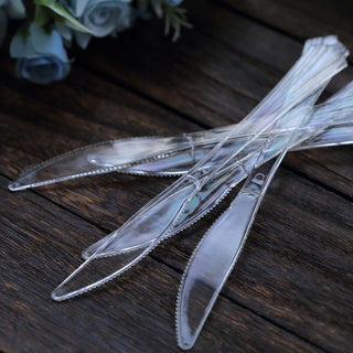 Clear disposable knives on a wooden surface.