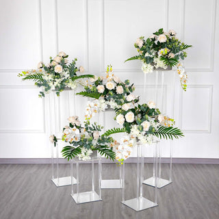 Elegant floral arrangements on clear stands for event decor.