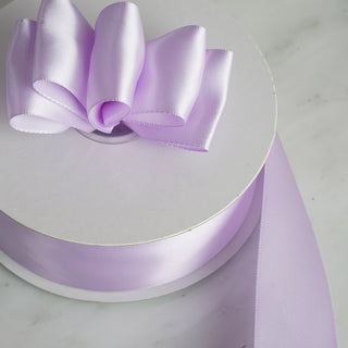 Light purple satin ribbon with bow on a white spool.