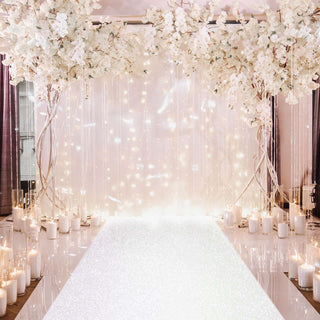 Elegant wedding backdrop with white flowers and candles, sparkling runway.