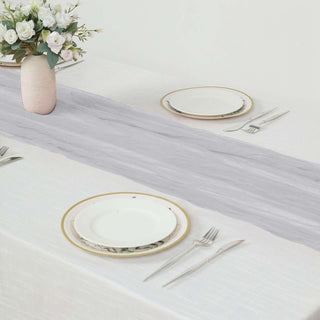Elegant table setting with a light gray runner and decorative vase of flowers.