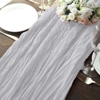 Wrinkled grey table runner with flowers on a dining table setting.
