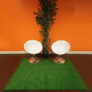 Two modern white chairs on a green rug against an orange wall.