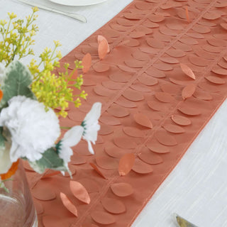 Coral leaf-patterned table runner on a white table setting.