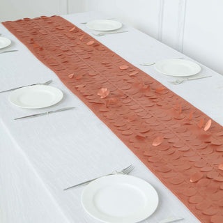 Copper leaf table runner on a white table with plates and cutlery.