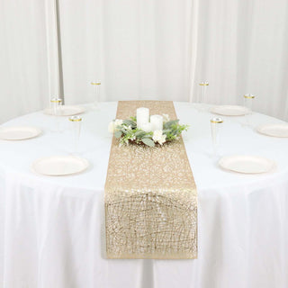 Gold lace table runner on a white table with candles and floral centerpiece.