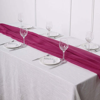 Pink table runner on a dining table set with plates and wine glasses.