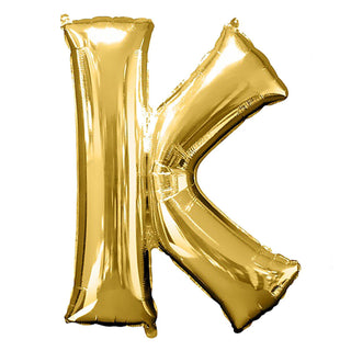 Gold foil balloon letter K on a plain background