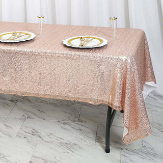 Rose gold sequin tablecloth draped over a table set with plates and glasses.