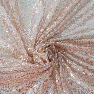 Shimmering sequin fabric in soft peach tones, elegantly twisted for texture.