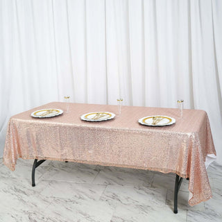 Rose gold sequin tablecloth on a dining table with elegant plates and cutlery.