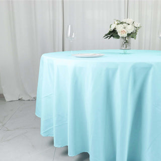Light blue tablecloth draped over a round table with floral centerpiece.