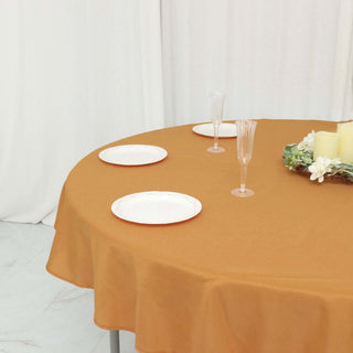Round mustard tablecloth with plates and glassware on a decorated table.