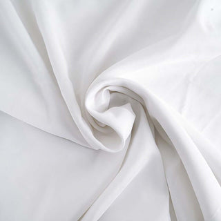 White silk fabric draped in soft folds, showcasing its smooth texture.