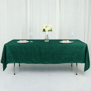Green tablecloth draped over a table set with flowers and dinnerware.