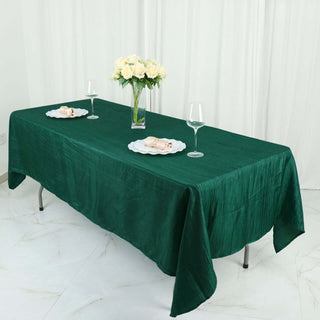 Green tablecloth elegantly draped on a dining table with flowers and glassware.