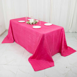 Pink tablecloth draped over a table set for a celebration.