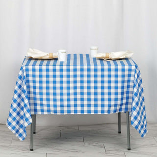 Blue and white checkered tablecloth on a dining table with napkins and cups.