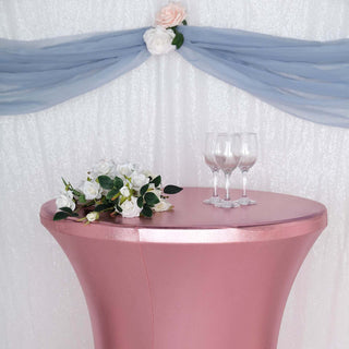 Pink table with floral arrangement and glasses, set against a decorated backdrop.