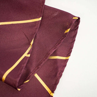 Burgundy silk fabric with gold geometric pattern detail.